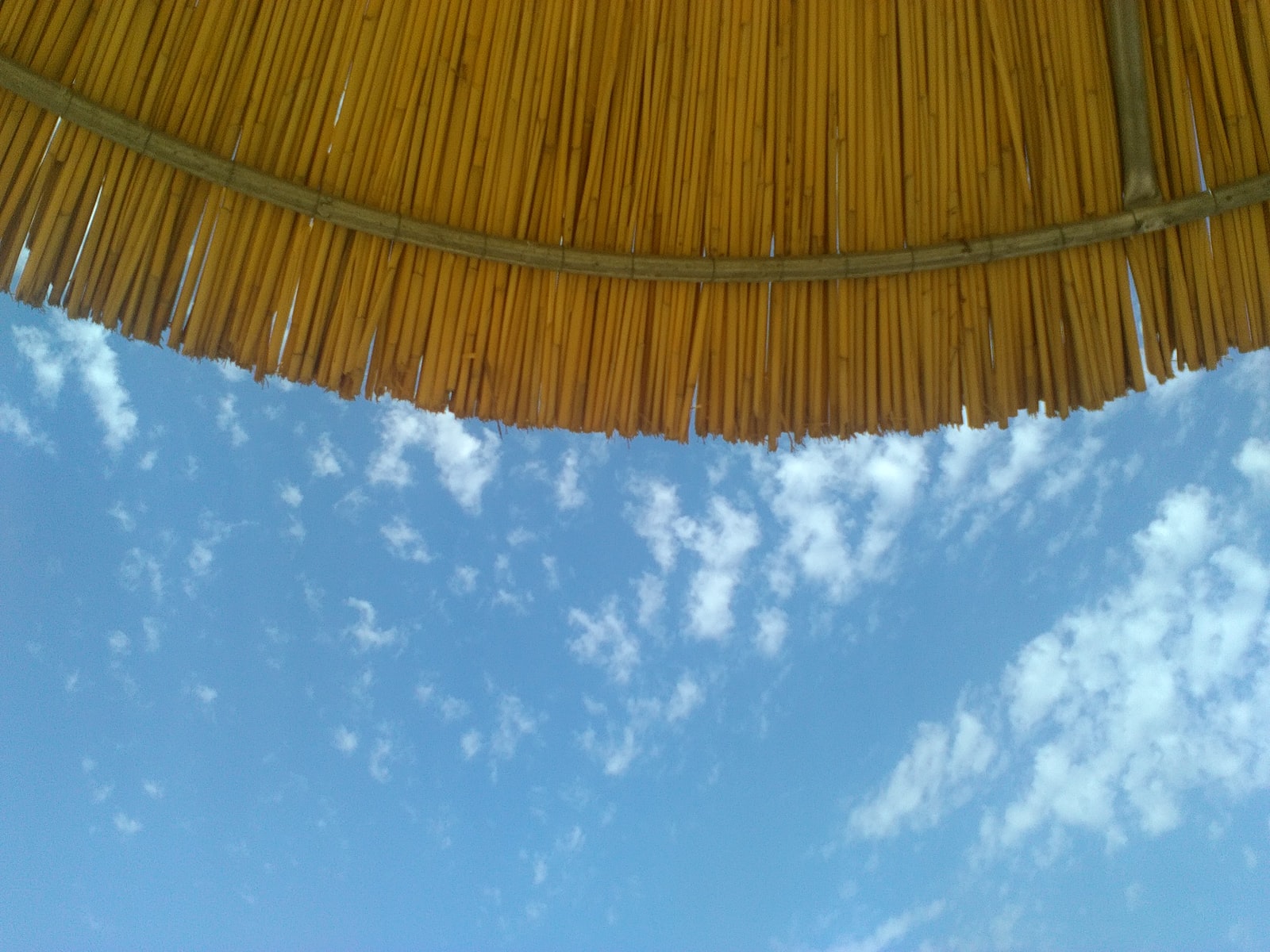 brown woven umbrella under blue sky and white clouds during daytime