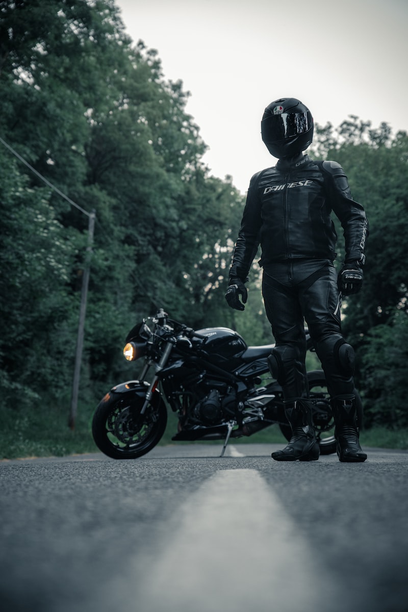 man in black jacket and helmet riding black motorcycle