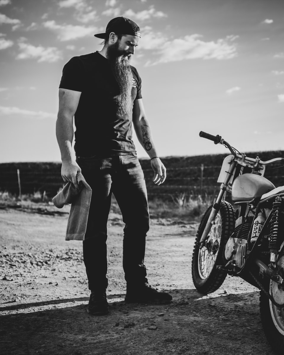 man in black t-shirt and pants standing beside motorcycle